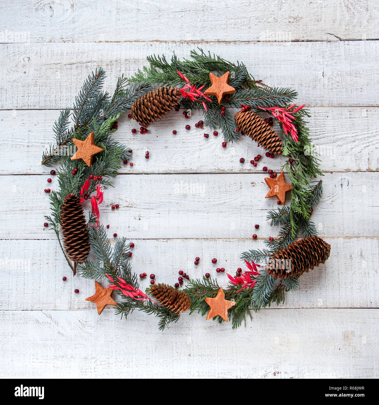 Christmas wreath in flat lay style made from pine cones, coconuts stars and red berries, square crop. Space for your product or text Stock Photo
