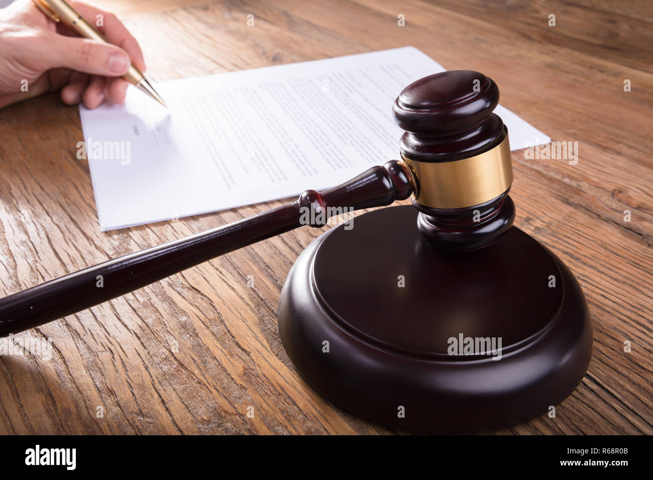 Gavel With Person's Hand Signing Legal Document Stock Photo Alamy