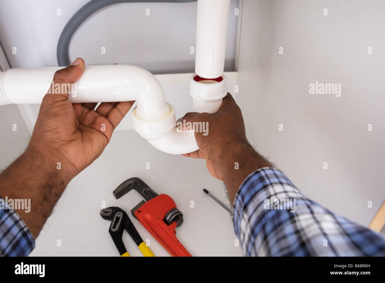 Plumber Fitting Sink Pipe In Kitchen Stock Photo