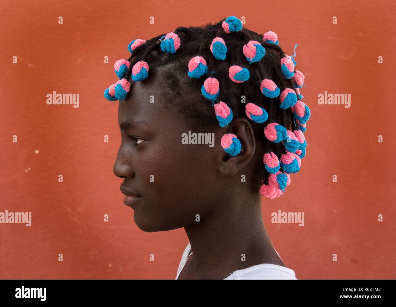 Portrait of a Angolan girl with the typical hairstyle made of braids with colorful scrunchies, Benguela Province, Catumbela, Angola Stock Photo