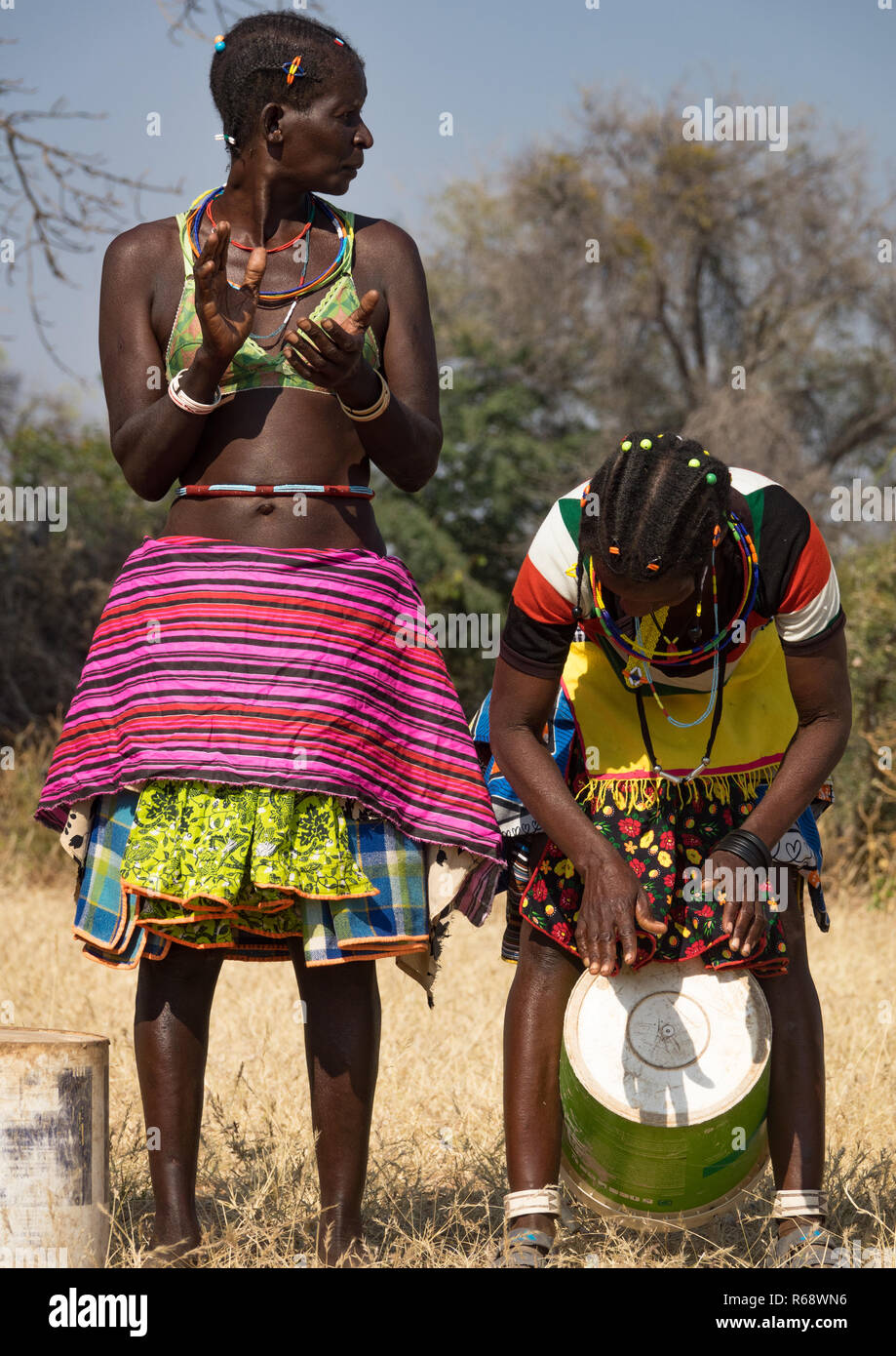 Mudimba tribe women playing music with a bucket and dancing, Cunene Province, Cahama, Angola Stock Photo