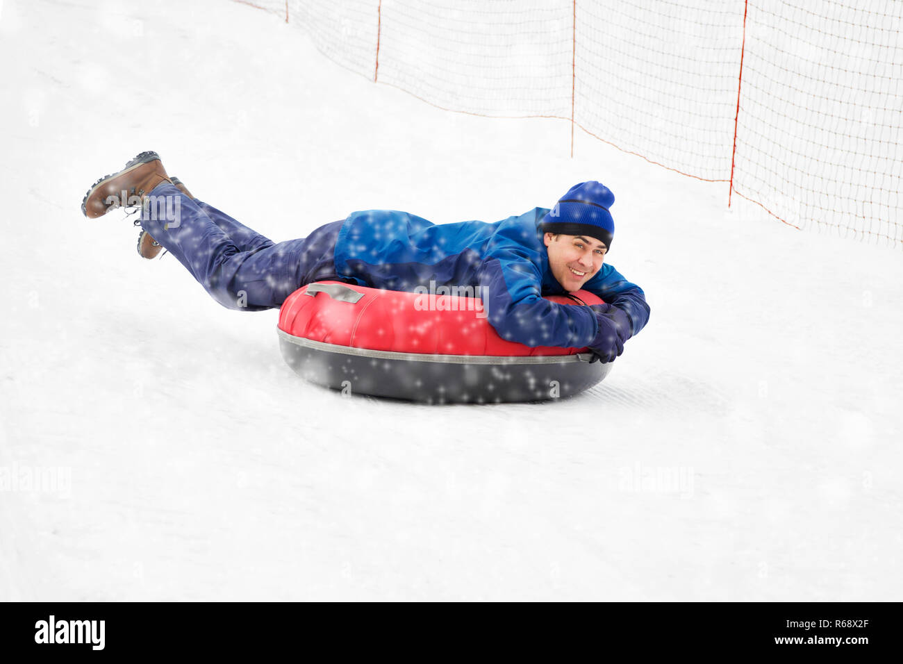 A happy man sliding down on snow tube at winter. Stock Photo