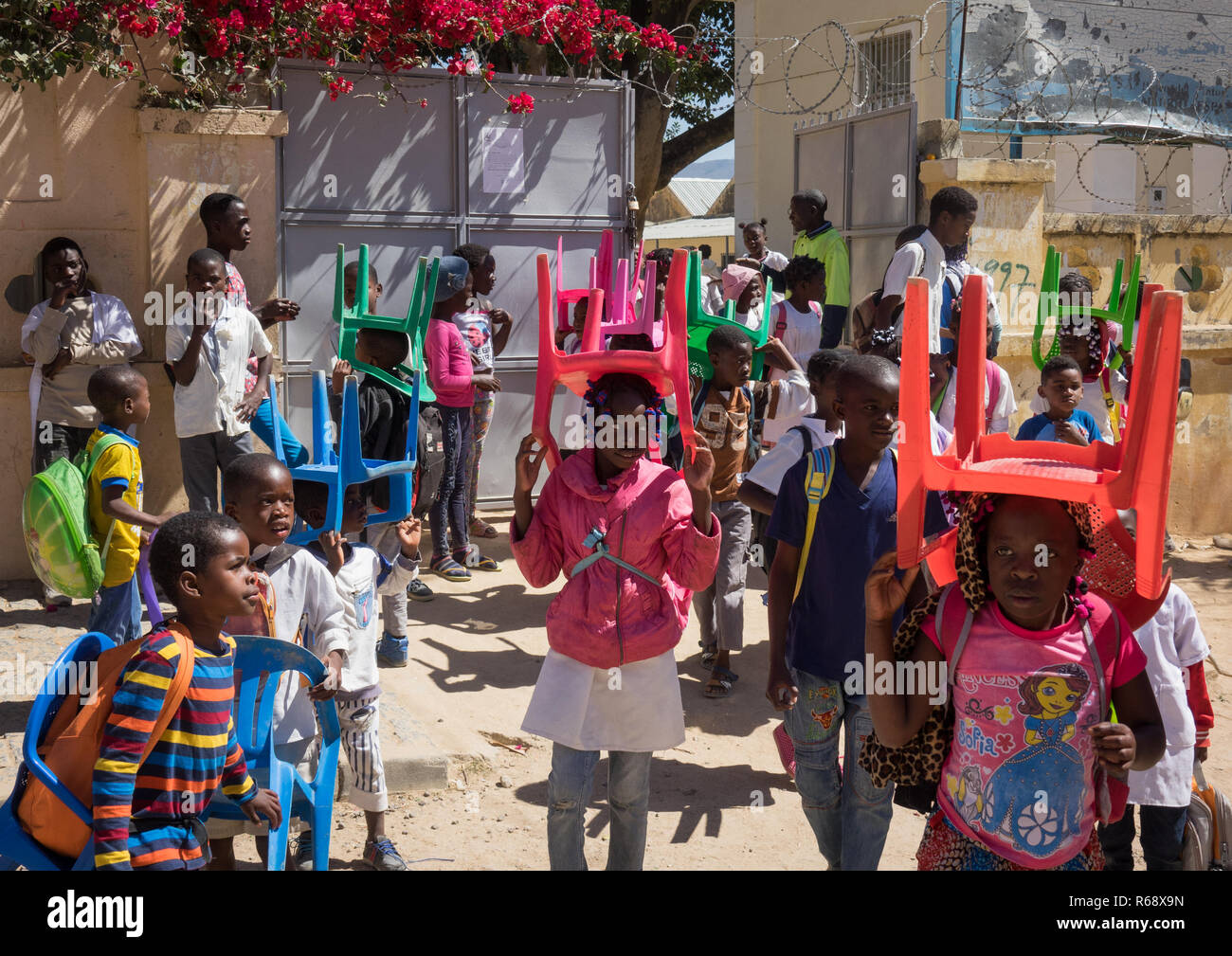Children going to school with their own chairs, as there are not enough