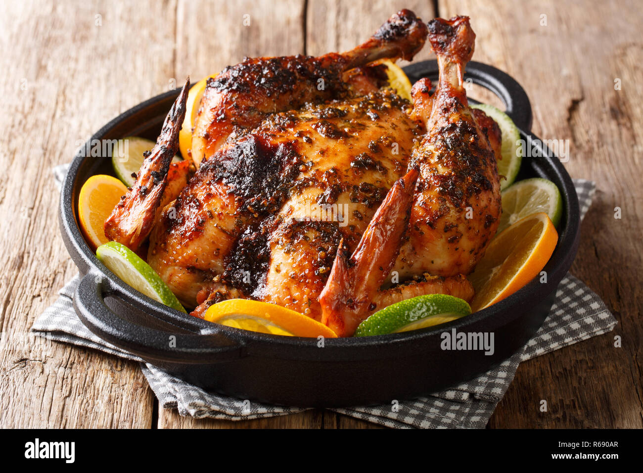 Traditional Cuban mojo chicken dish baked and served with fresh oranges and limes closeup in a pan on the table. horizontal Stock Photo