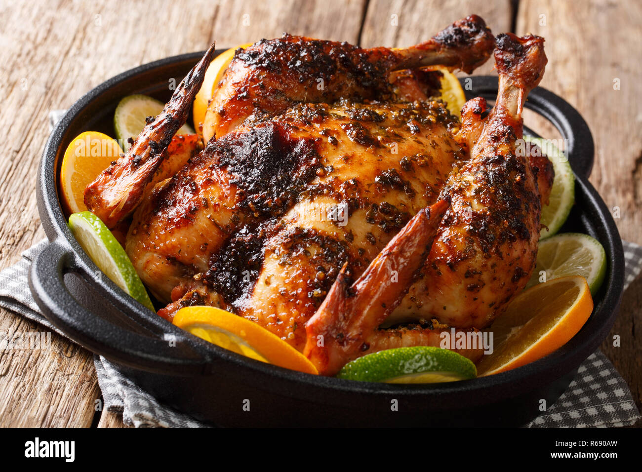 Spicy Cuban Mojo Chicken served with fresh oranges and limes close-up in a frying pan on the table. horizontal Stock Photo