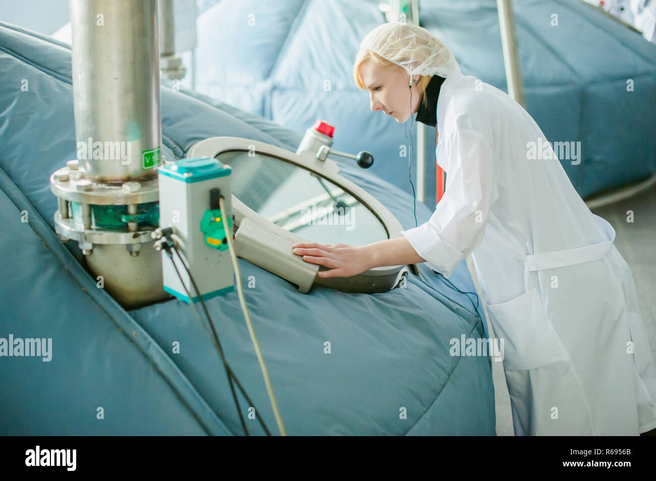 On the territory of brewer's plant with steel fermentation vats. female