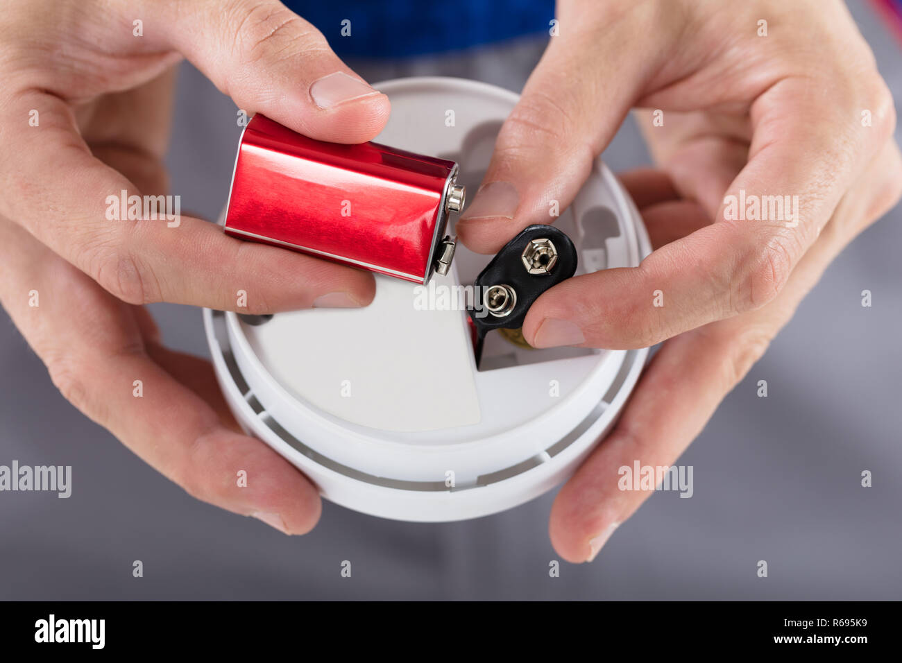 Person's Hand Inserting Battery In Smoke Detector Stock Photo