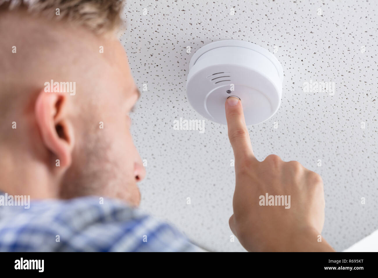 Person's Hand Installing Smoke Detector On Ceiling Stock Photo