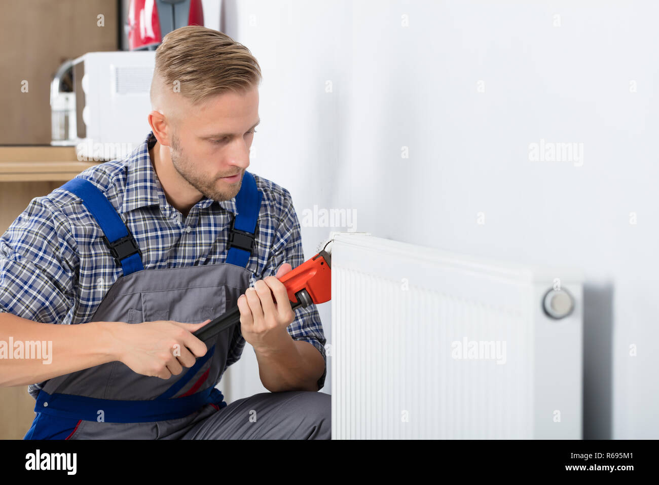 Male Plumber Fixing Thermostat Using Wrench Stock Photo