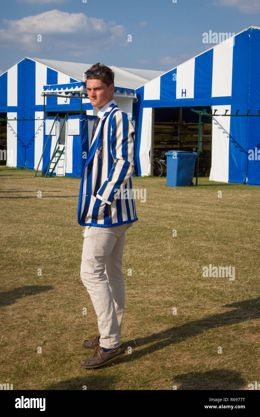 A young rower in a blue and white striped rowing blazer stands in front