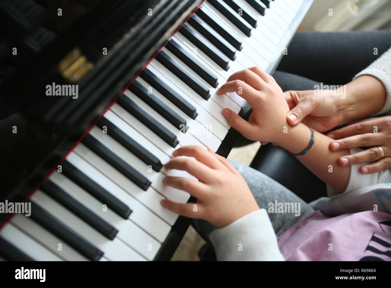 A teacher teaches playing the piano her student. Stock Photo