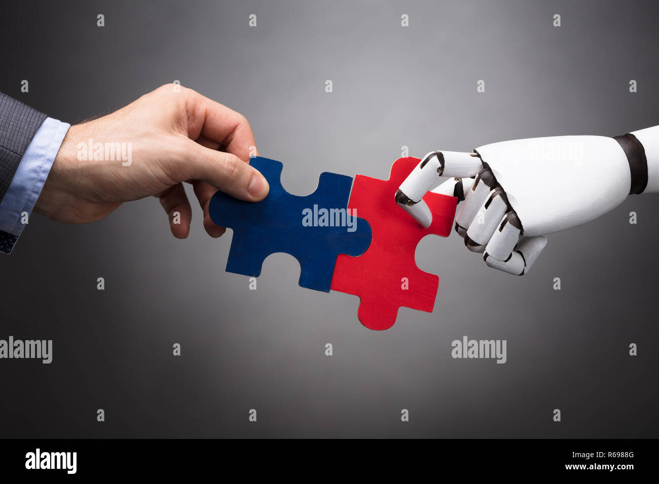 Businessperson And Robot Holding Jigsaw Puzzle Stock Photo - Alamy