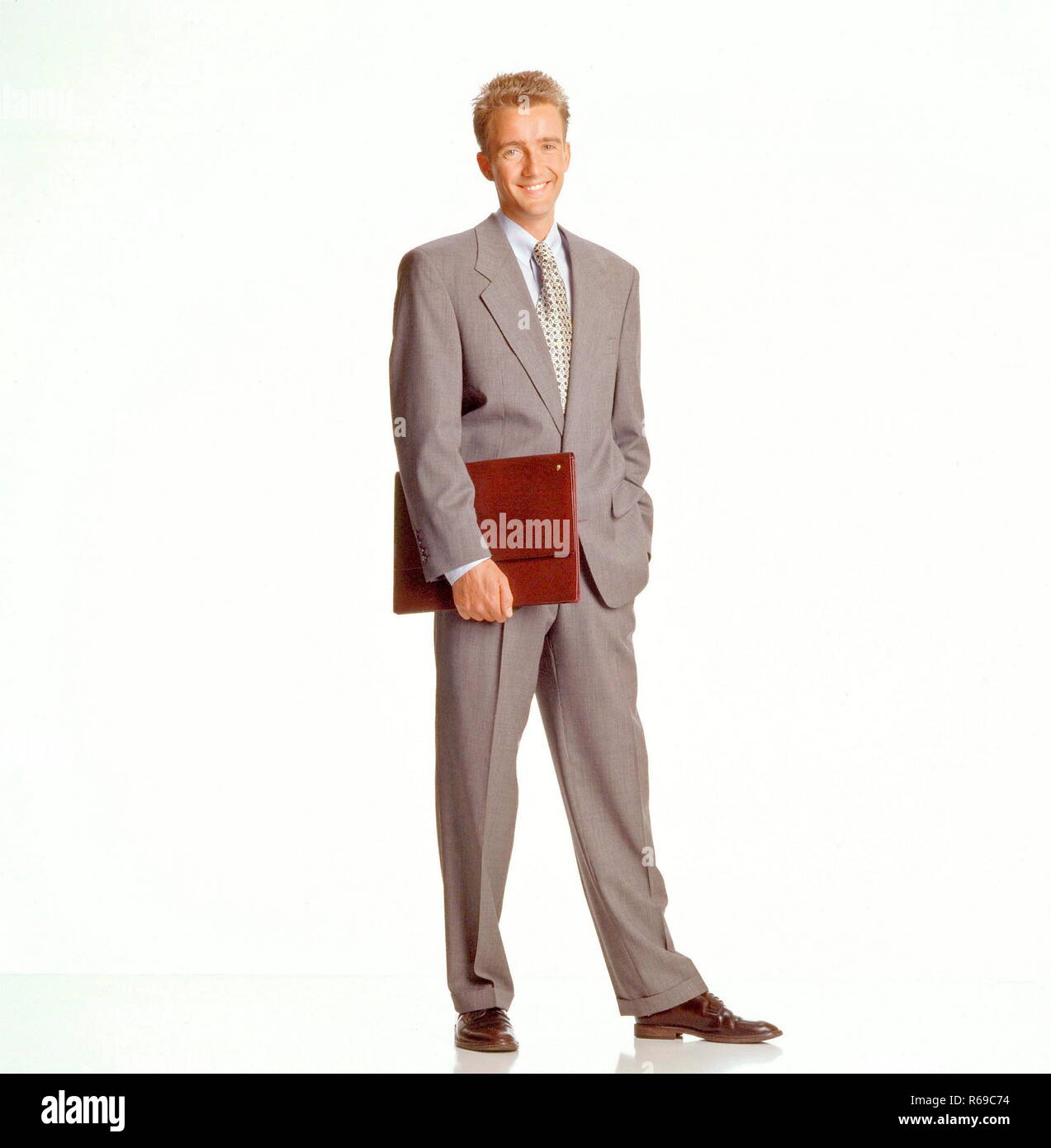 Portrait, Ganzfigur, junger Mann mit kurzen blonden Haaren bekleidet mit grauem  Anzug, weissem Hemd und Krawatte und Aktentasche Stock Photo - Alamy