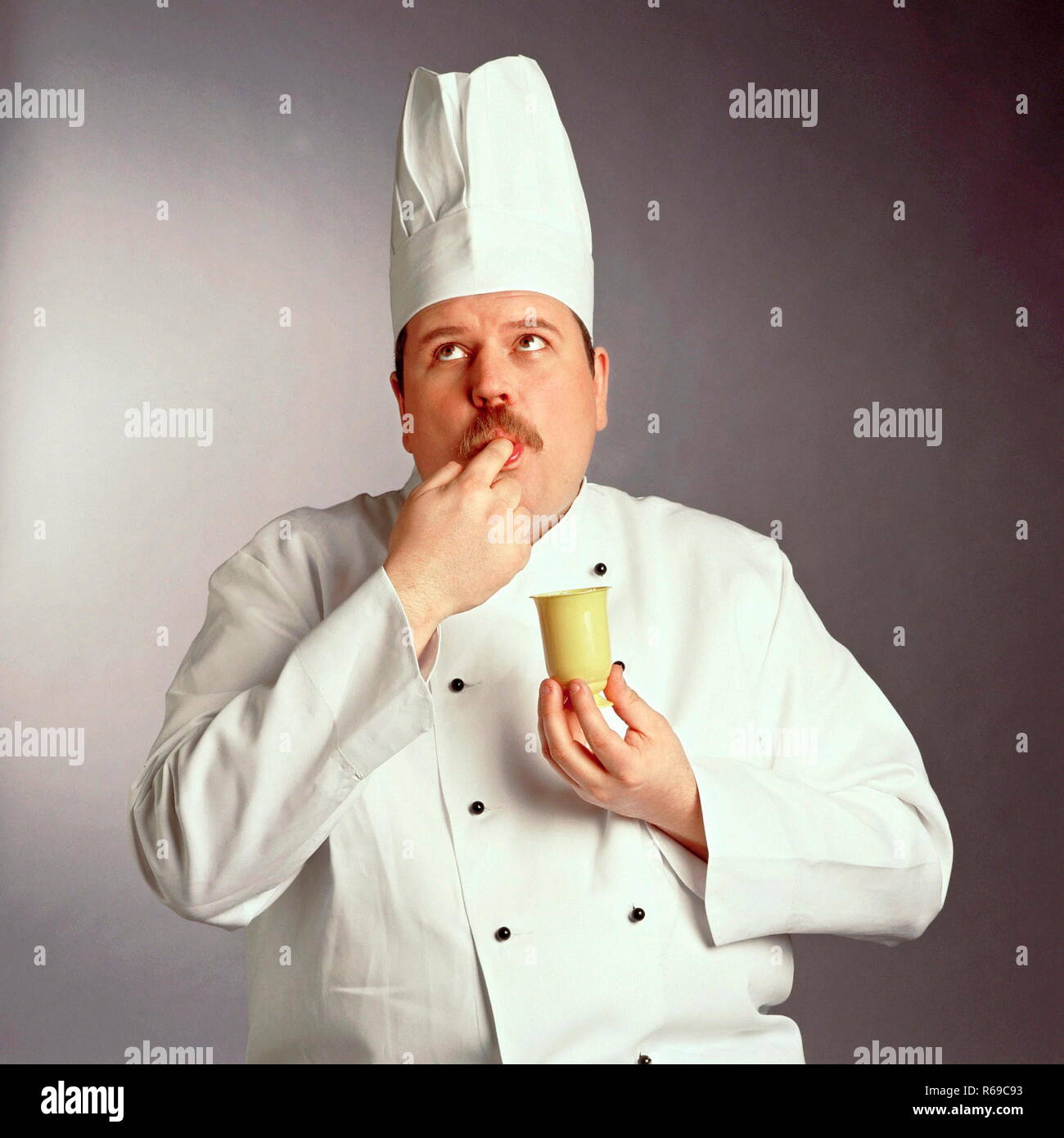 Portrait, Halbfigur, Koch in Arbeitskleidung probiert ein Dessert Stock Photo