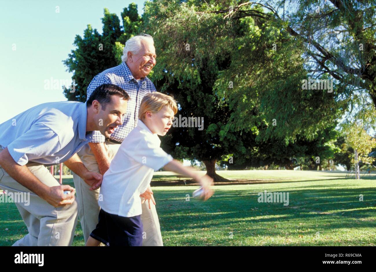 Portrait, Parkszene, 3 Generationen, Grossvater, Vater und Sohn, 7 Jahre, spielen auf einer Wiese Boule Stock Photo