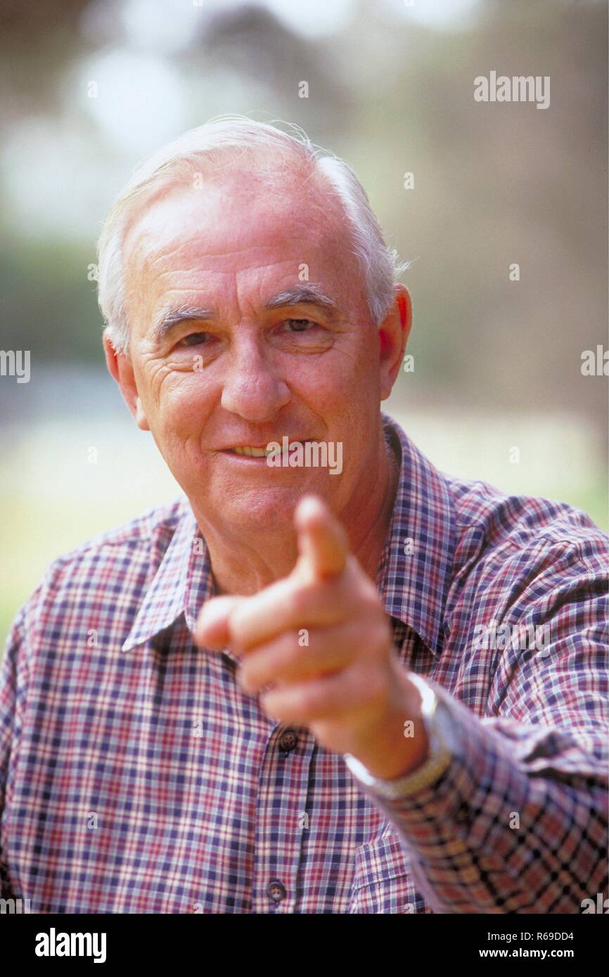 Portrait, Outdoor, weisshaariger Senior bekleidet mit kariertem Hemd, ca. 70 Jahre alt, zeigt mit dem Finger auf den Betrachter Stock Photo