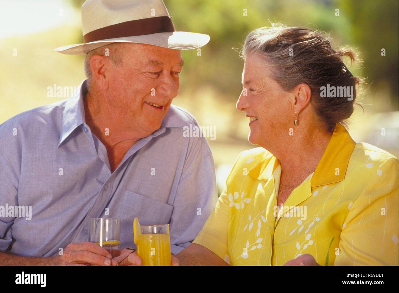 Portrait, Outdoor, Seniorenpaar Mitte 60 sitzt mit einem Glas Saft in der Hand im Sommer im Garten Stock Photo