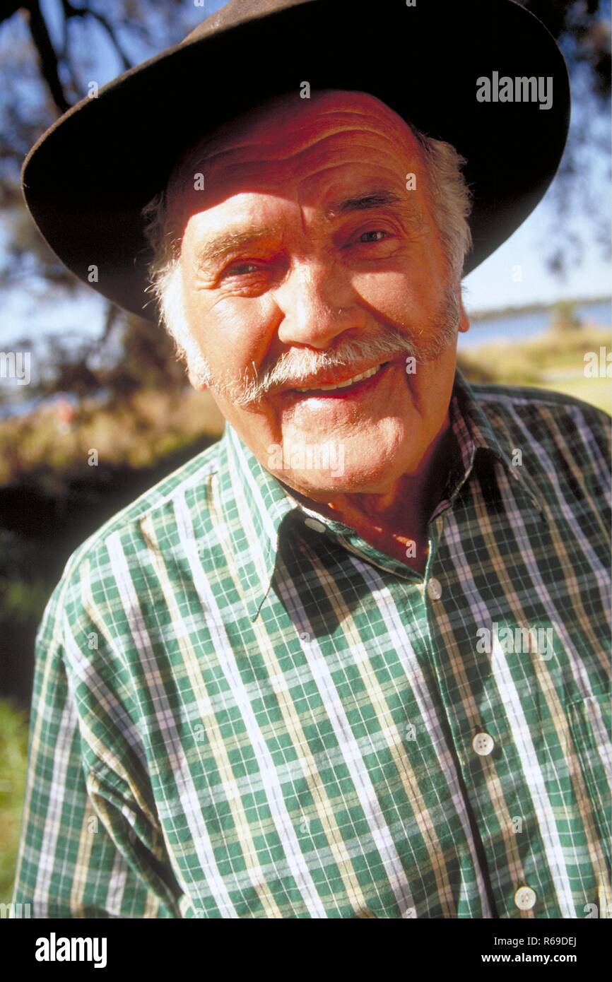 Portrait, Outdoor, Mann mit Oberlippenbart, ca. 65 Jahre alt, bekleidet mit gruen-weiss kariertem Hemd und Hut Stock Photo