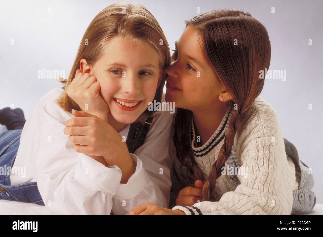 Portrait, Innenraum, 2 8 12jaehrige Maedchen mit langen Haaren bekleidet mit Jeanslatzhosen