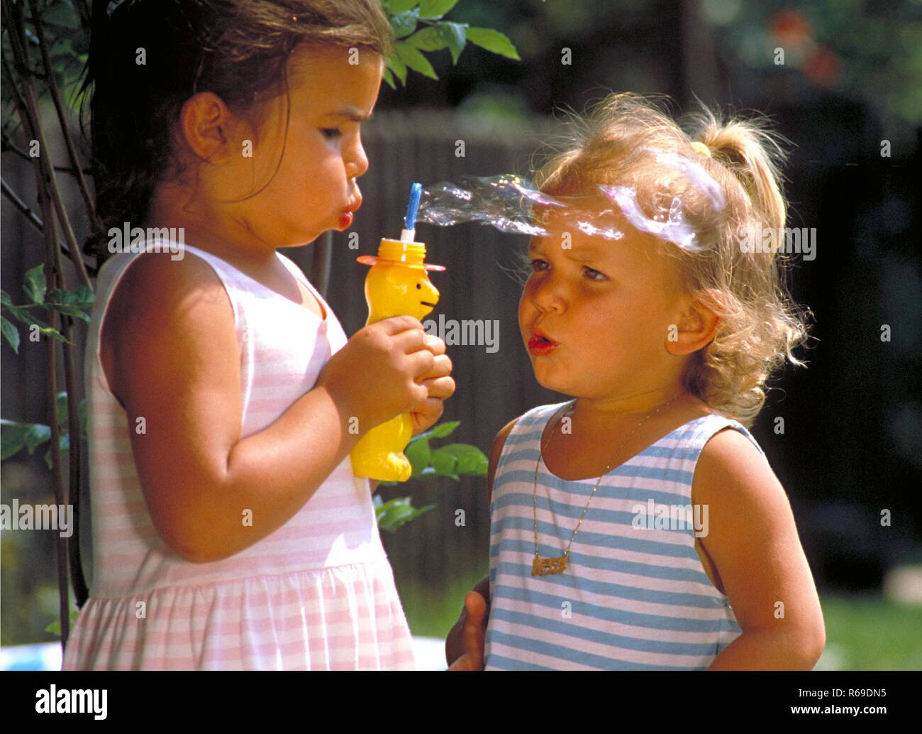 2 kleine maedchen spielen im Garten mit Seifenblasen Stock Photo Alamy
