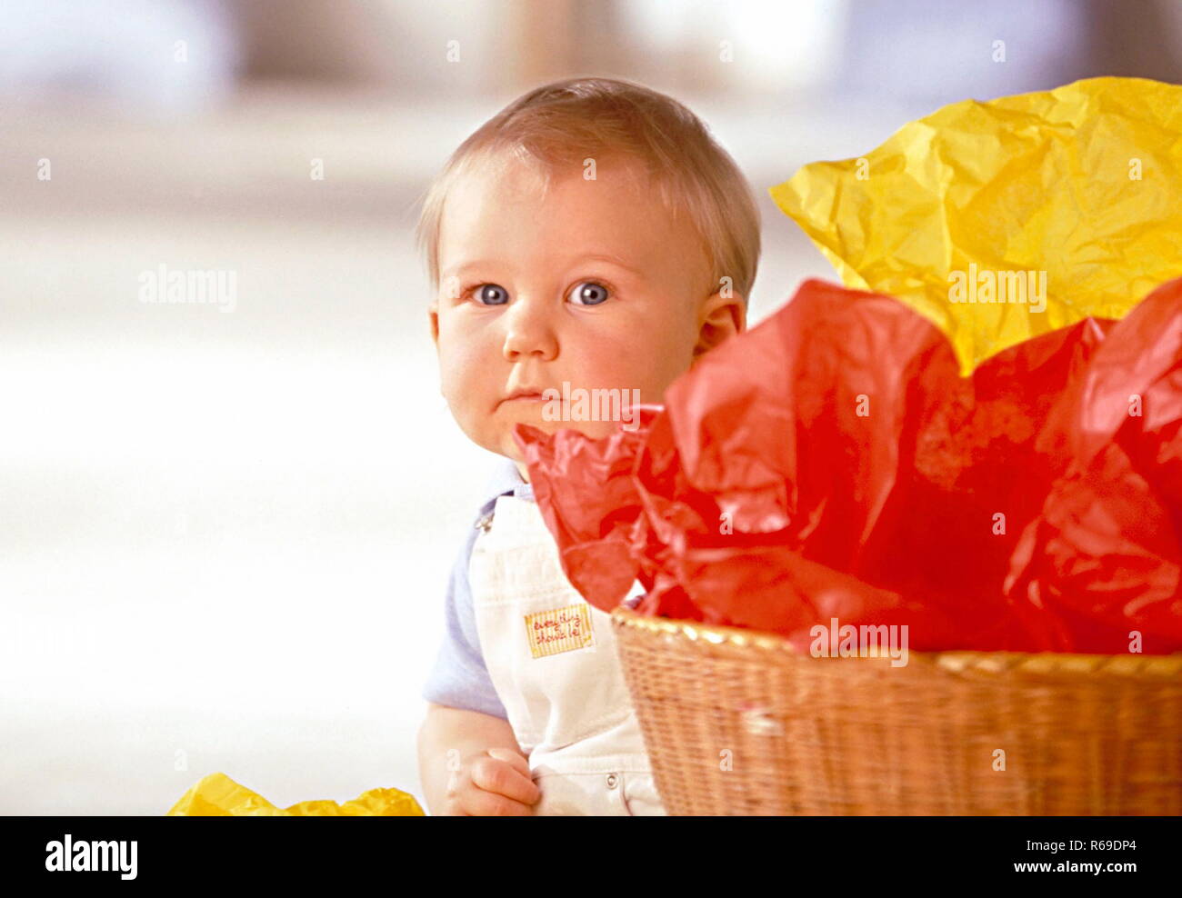 Portrait eines kleinen Jungen hinter einem Korb mit roten und gelben Plastiktueten Stock Photo