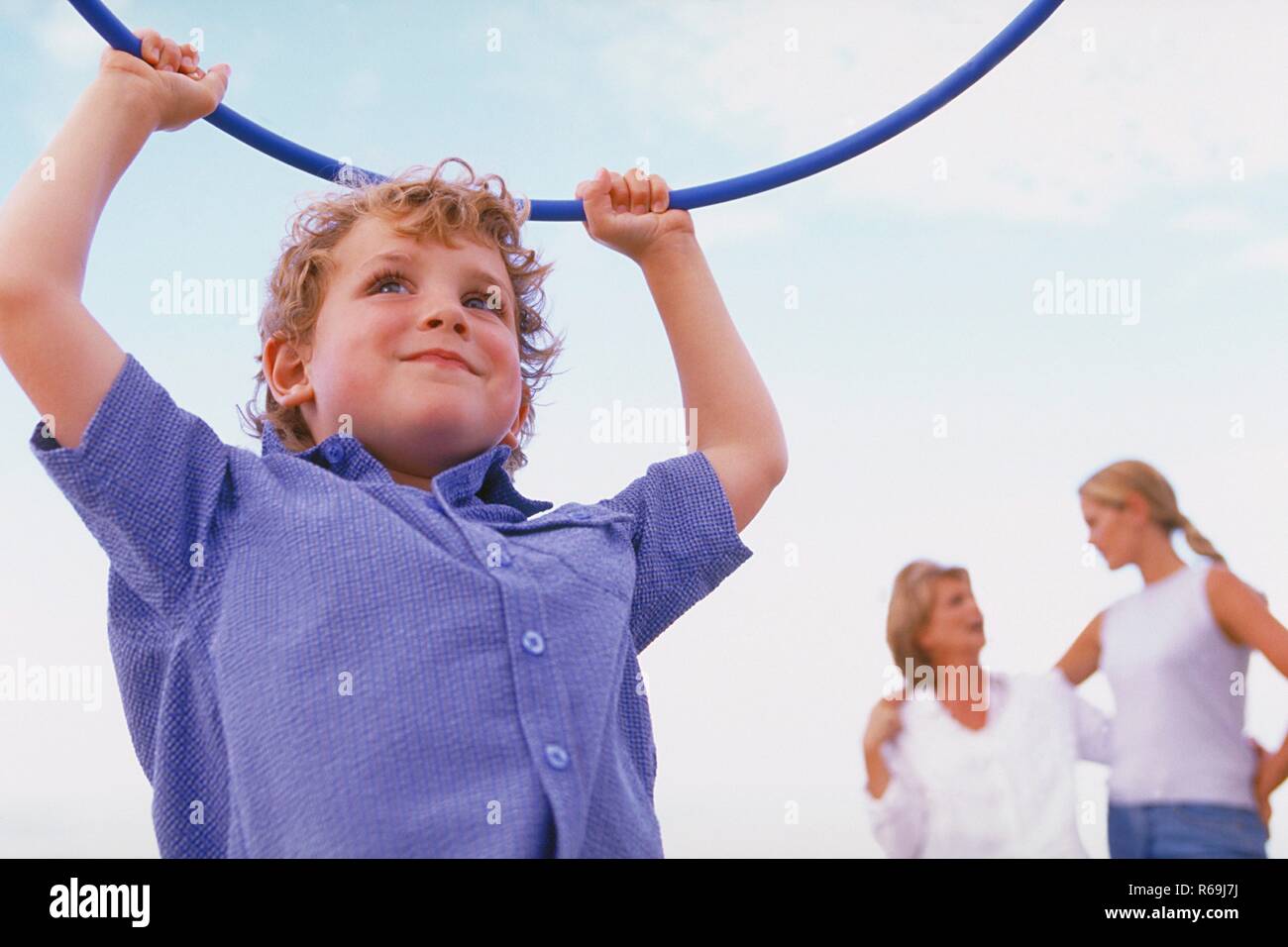 Strandszene, Portrait, Halbfigur, Junge, 5 Jahre, bekleidet mit blau-weiss kariertem Hemd, spielt mit einem blauen Gymnastik Reifen am Strand Stock Photo