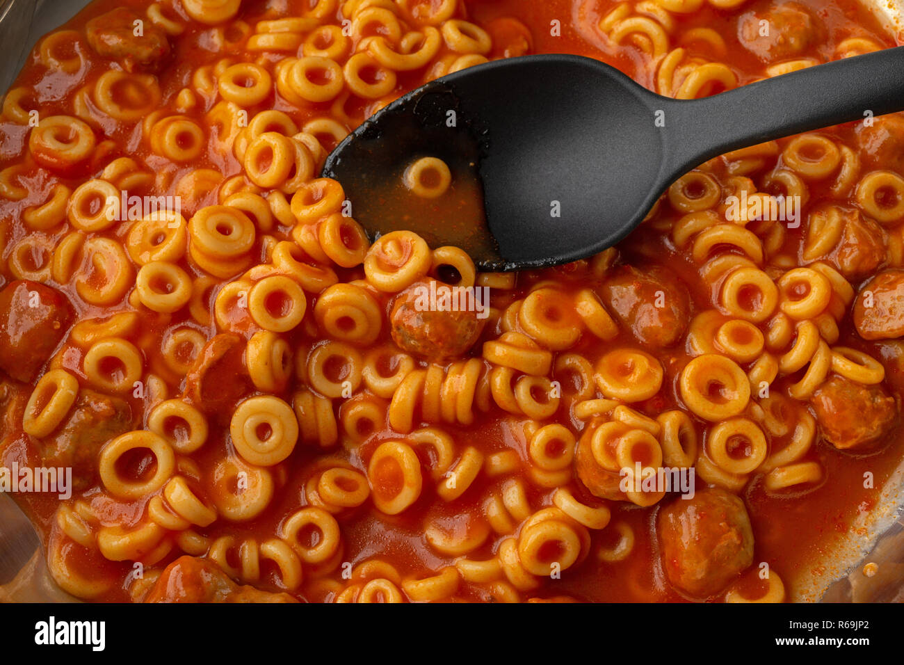 Canned spaghetti rings with meatballs cooking in a pan with a single
