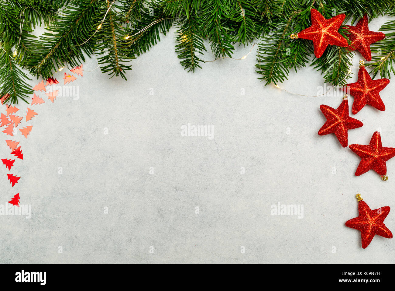 Christmas background with fir tree and red shiny stars on gray concrete table. Top view with copy space. Stock Photo