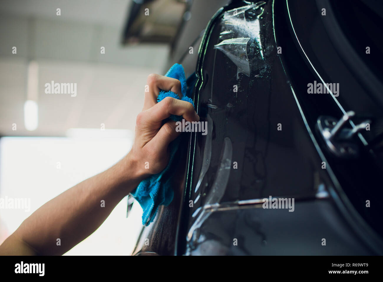 Car wrapping, mechanic with squeegee installs film Stock Photo by NomadSoul1
