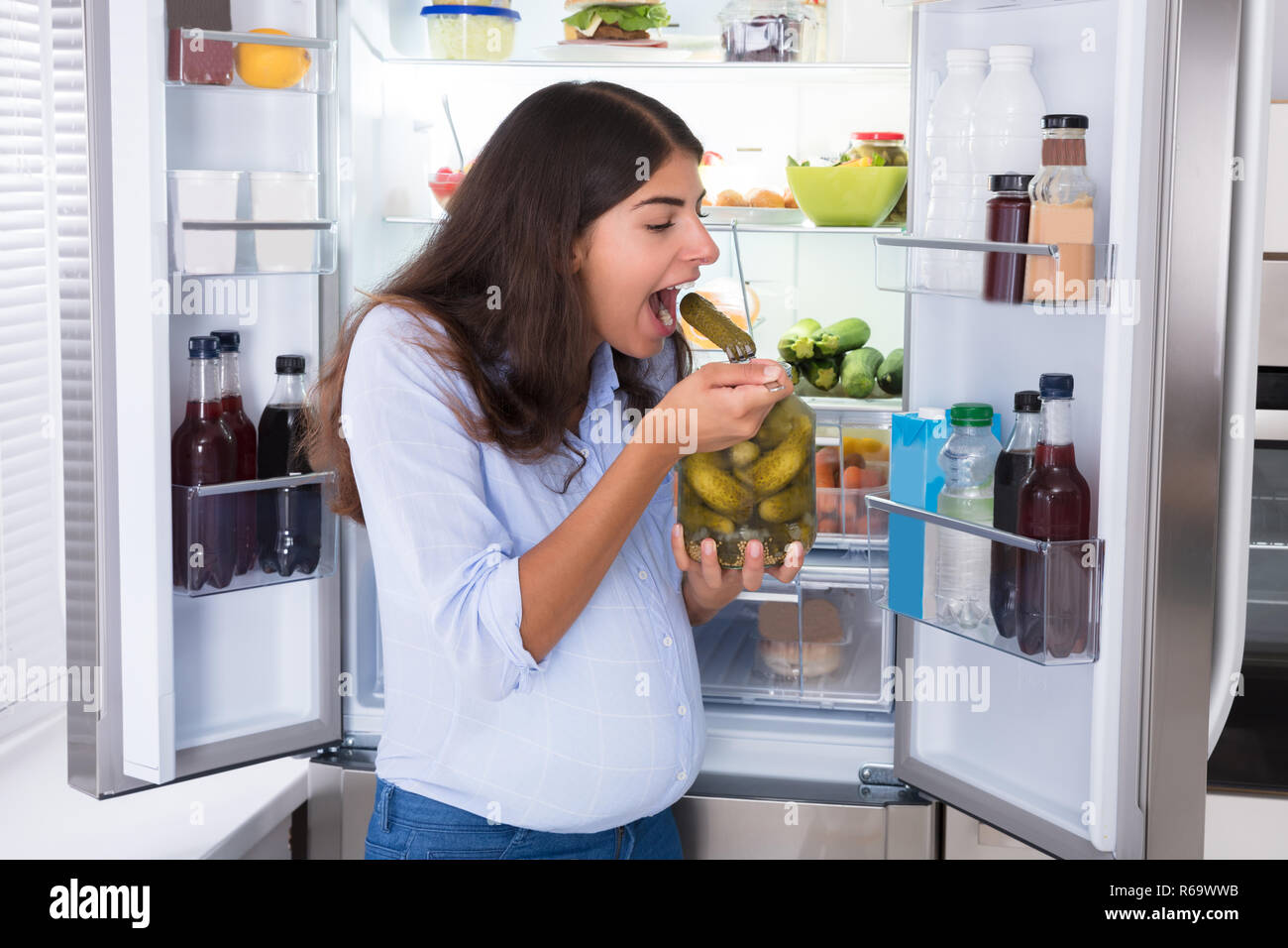 Young Woman Eating Pickle Stock Photo
