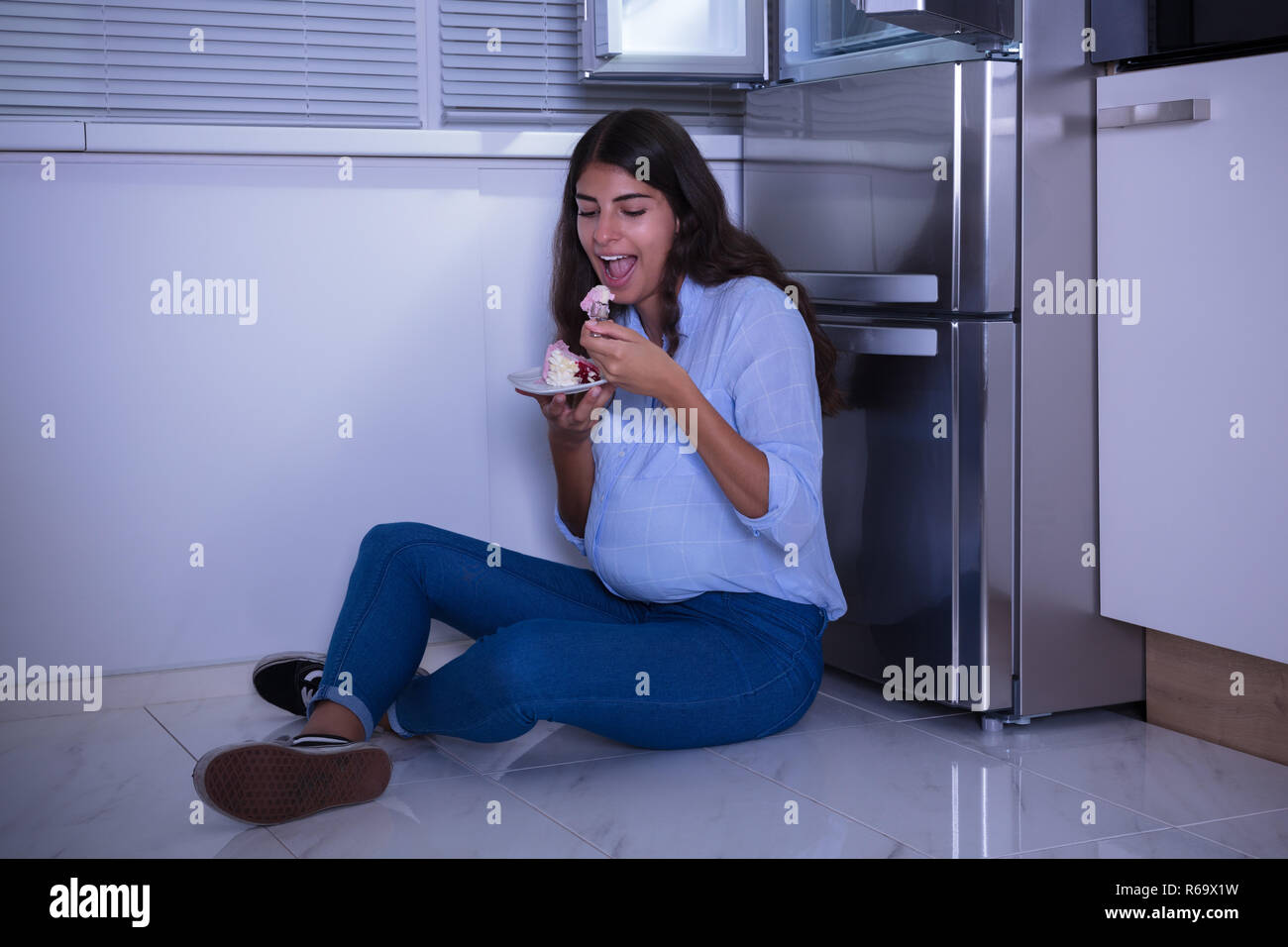 Young Woman Eating Slice Of Cake Stock Photo