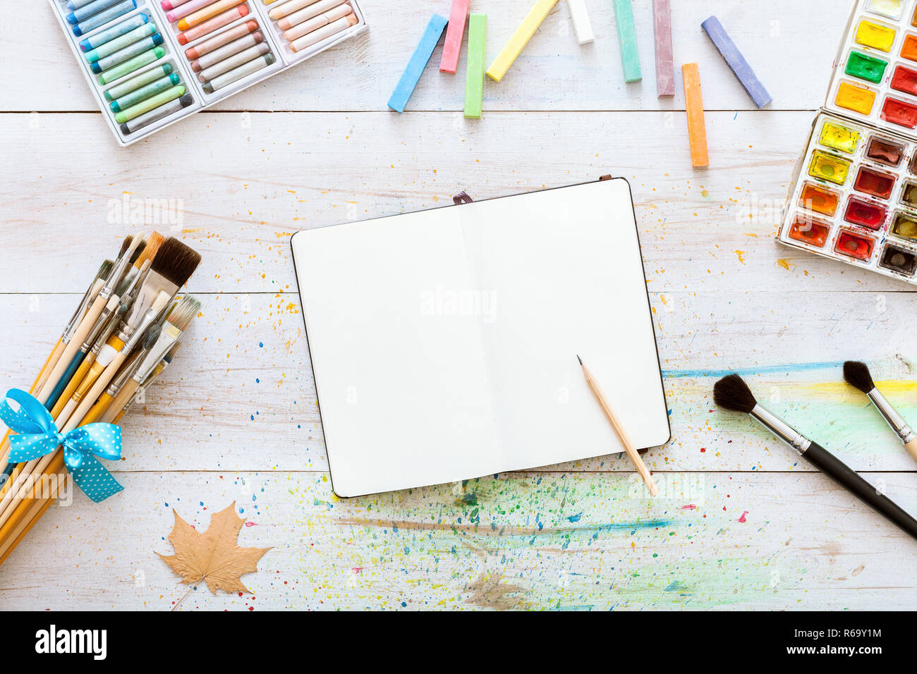 Artistic creative design workspace, notebook mock up for artwork with watercolor paints, pencil
