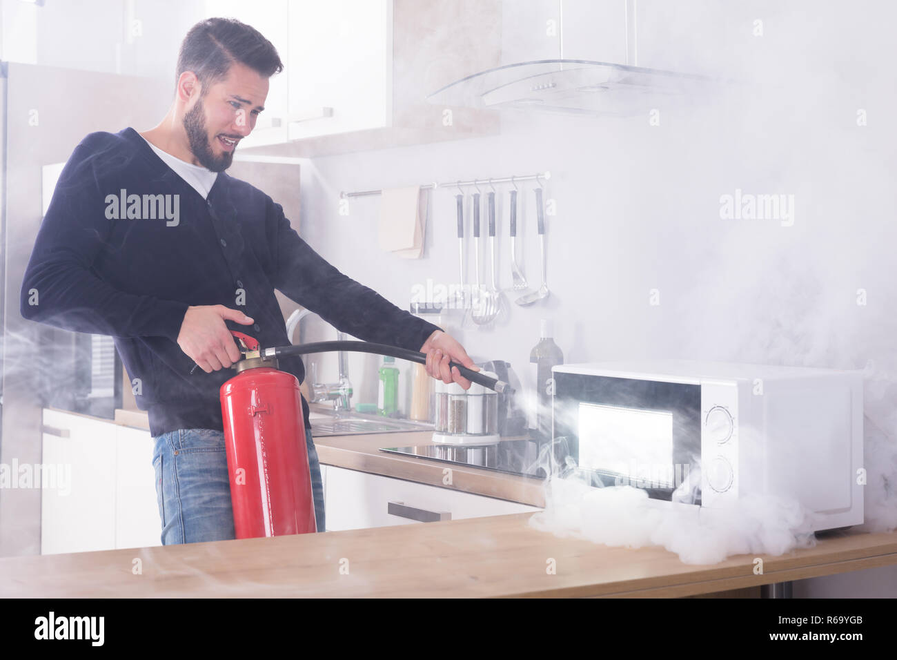 Man Spraying Fire Extinguisher On Microwave Oven Stock Photo Alamy
