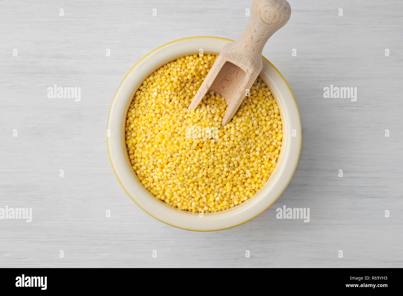 Organic millet seeds in a ceramic bowl on wooden white rustic table.Supergrain with its mildly sweet flavor, is tasty, soothing, non-acid forming, and Stock Photo