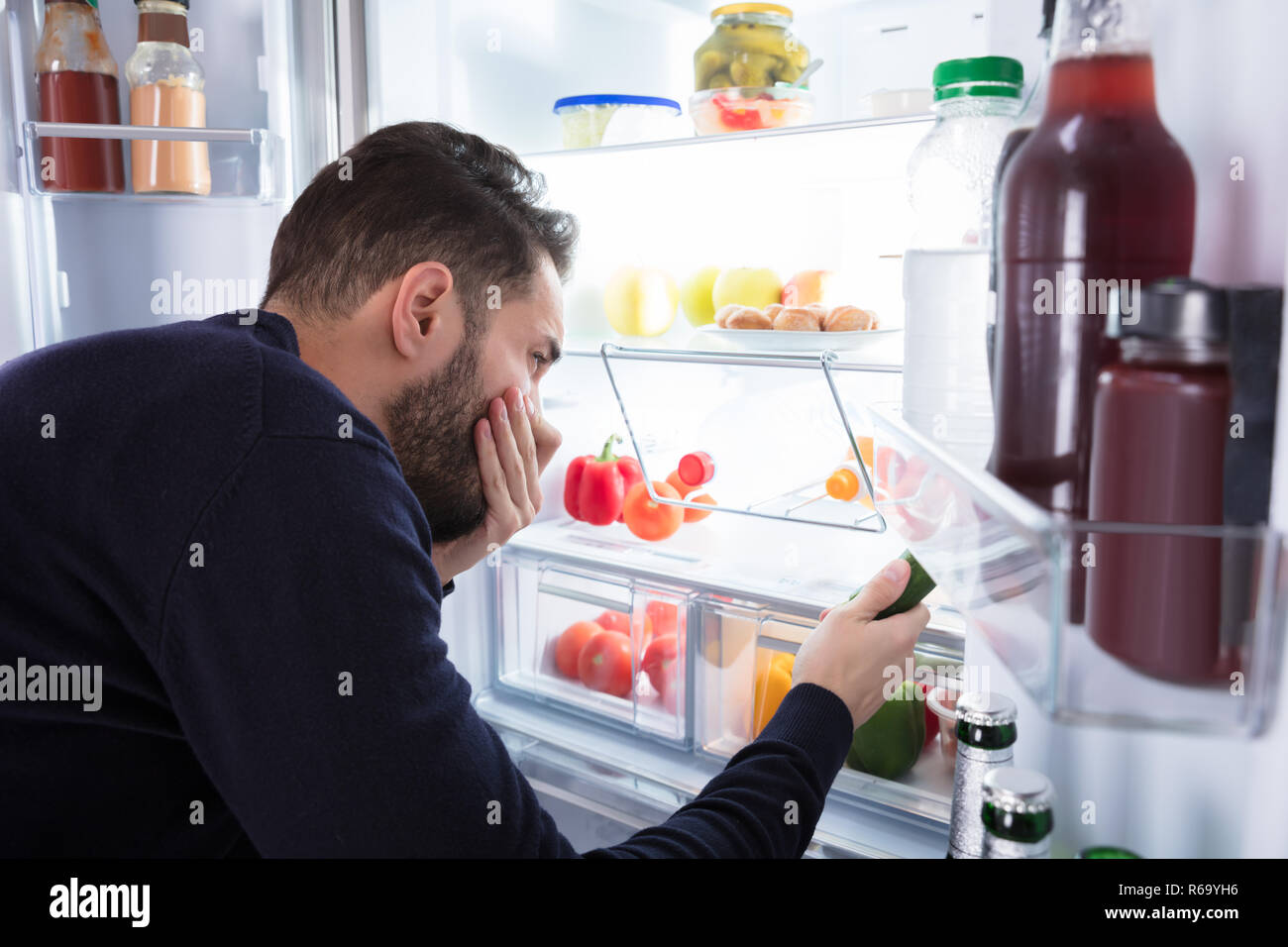 Man Noticing Smell Coming From Foul Food In Refrigerator Stock Photo