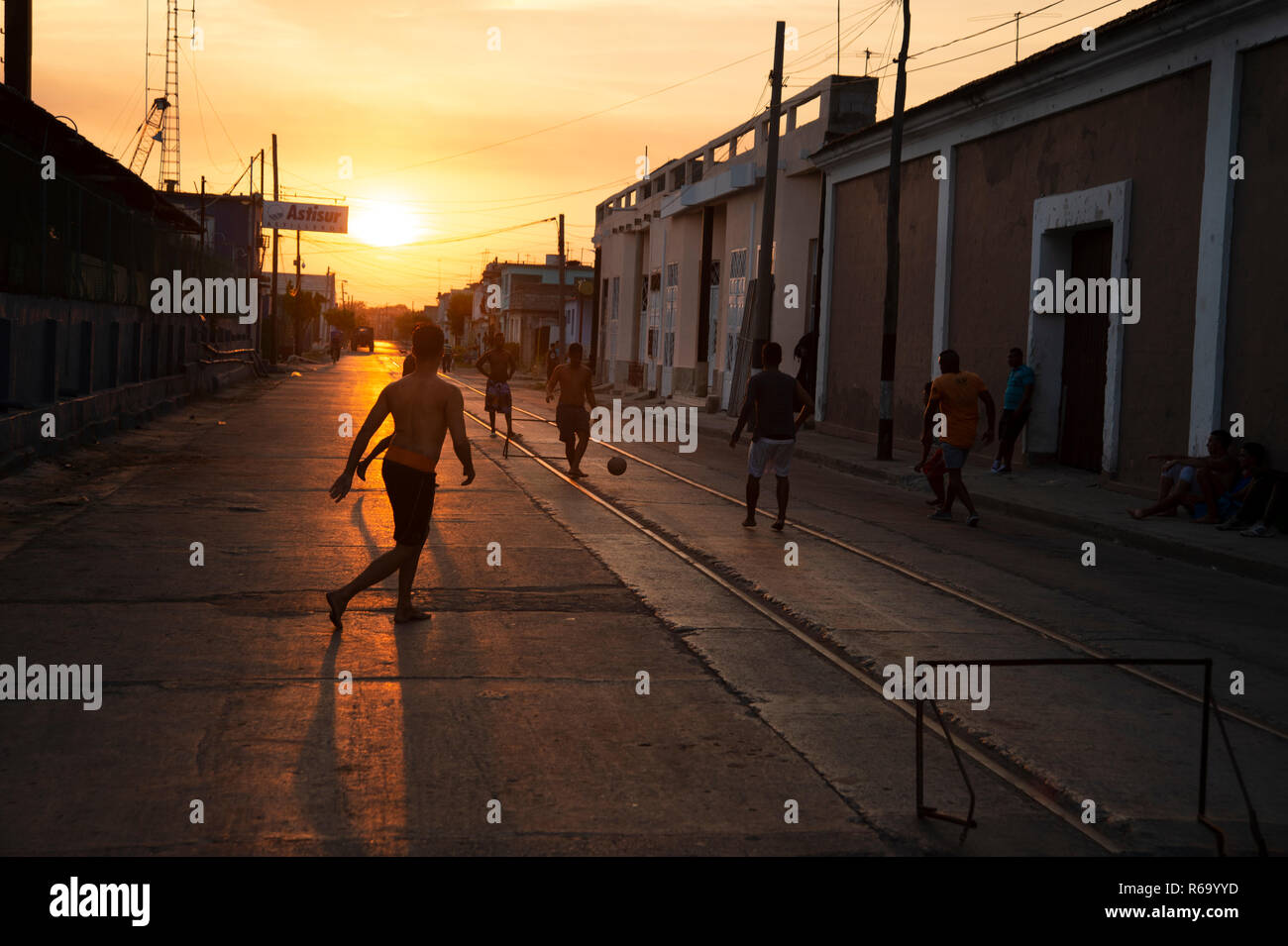 Silhouettes of Cuban boys playing street football as the sun sets behind them  in Cienfuegos Cuba Stock Photo