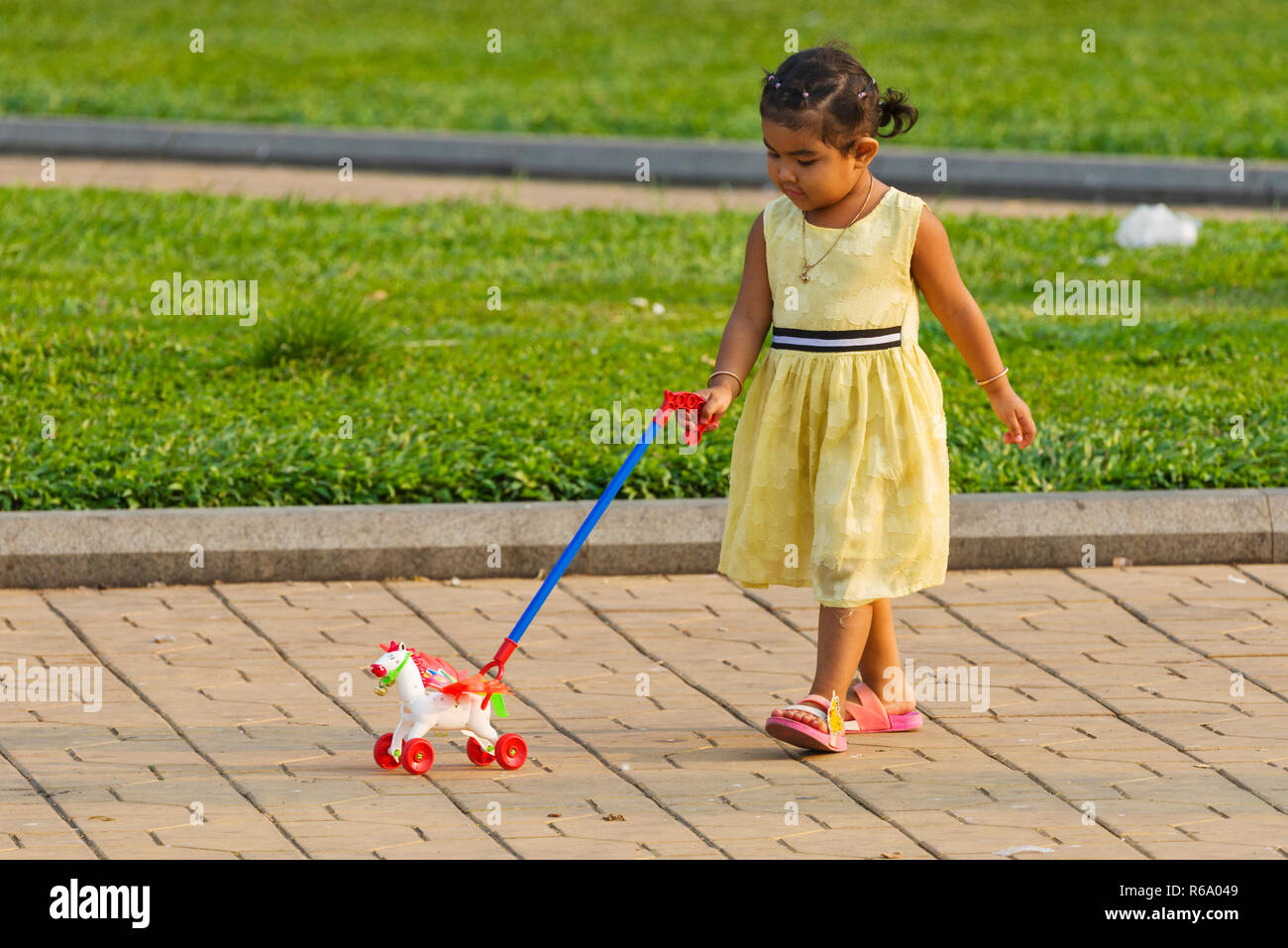 child discovering his new toy in the park of the royal palace in Phnom Penh, Cambodia Stock Photo