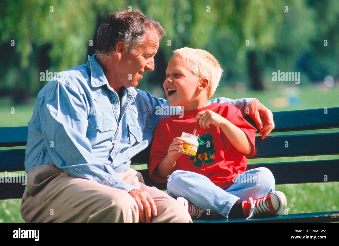 Portrait, Opa und Sohn im Gespraech auf einer Parkbank Stock Photo