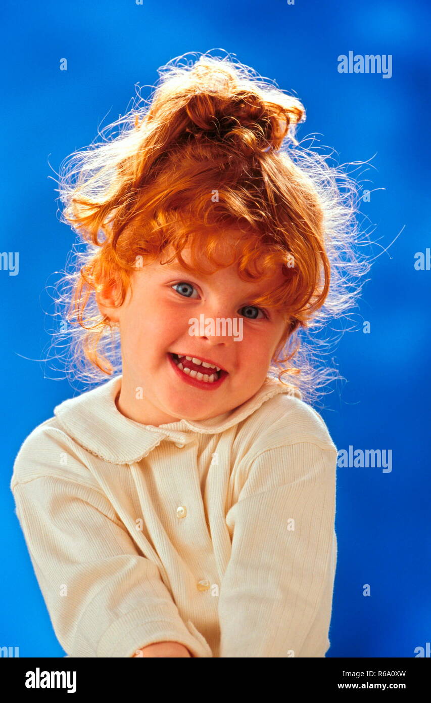 Portrait, rothaariges Maedchen mit blauen Augen, 4 Jahre, traegt naturfarbene Bluse vor blauer Hintergrund Stock Photo