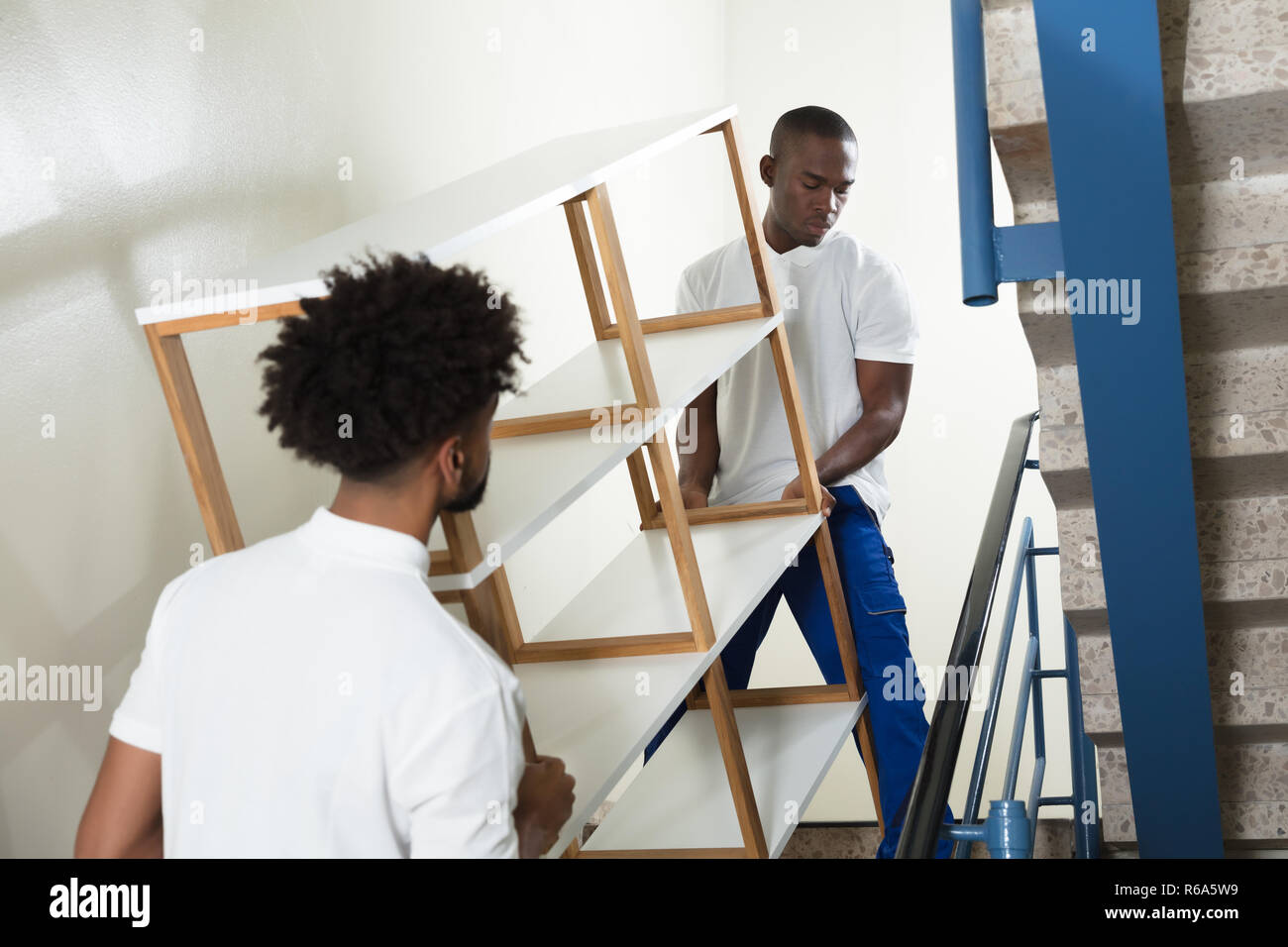 Two Male Movers Carrying The Empty Shelf At Home Stock Photo Alamy