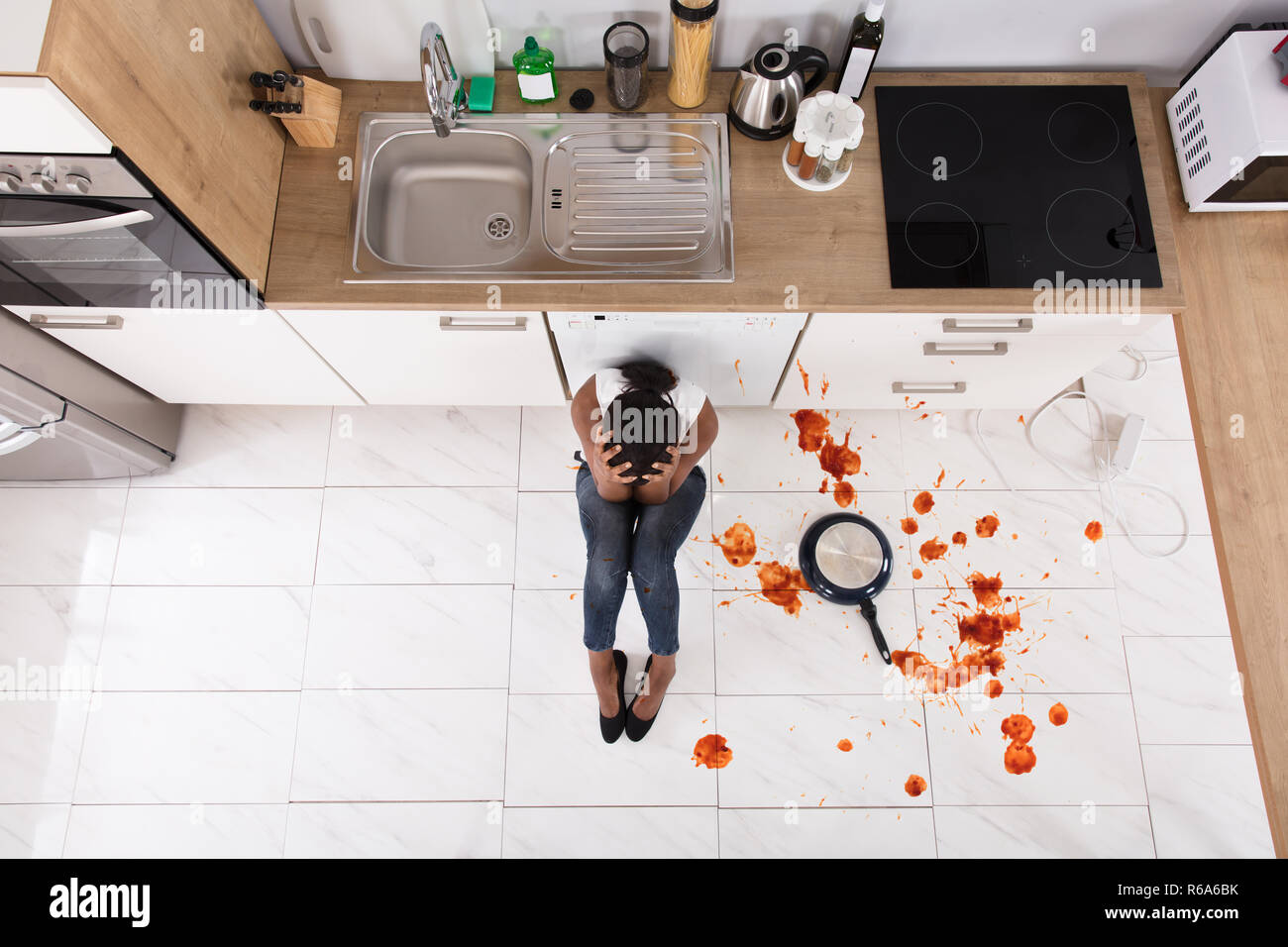Woman Sitting On Kitchen Floor With Spilled Food Stock Photo - Alamy