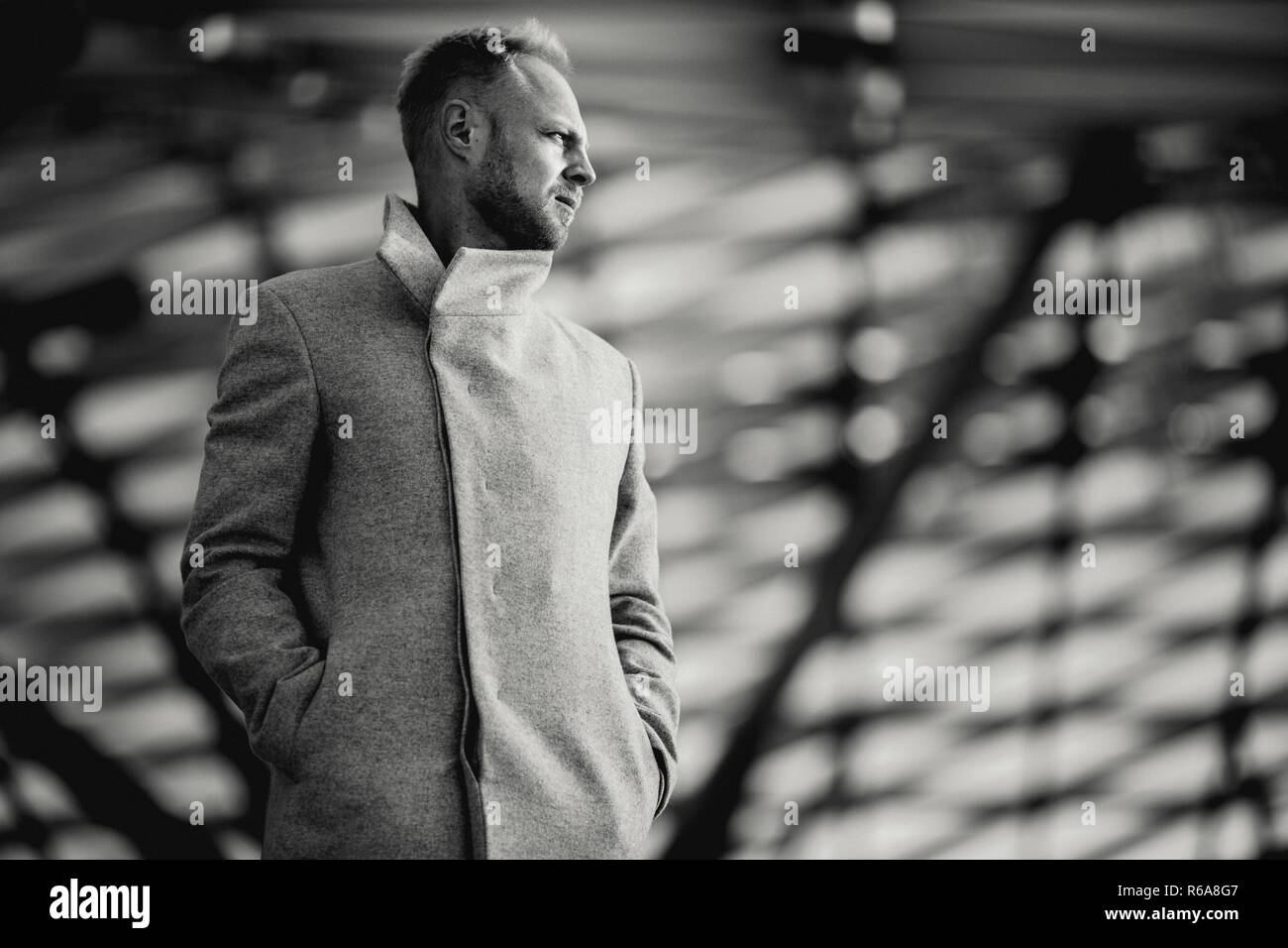 Black and white photo under film of serious man in coat under glass roof Stock Photo