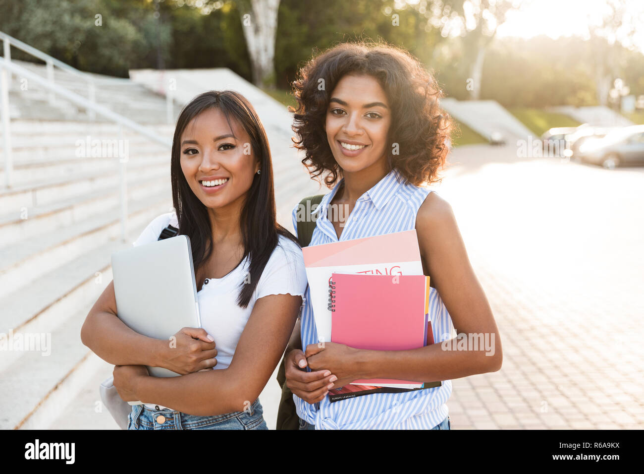 Two happy young students girls standing outdoors, holding books Stock ...