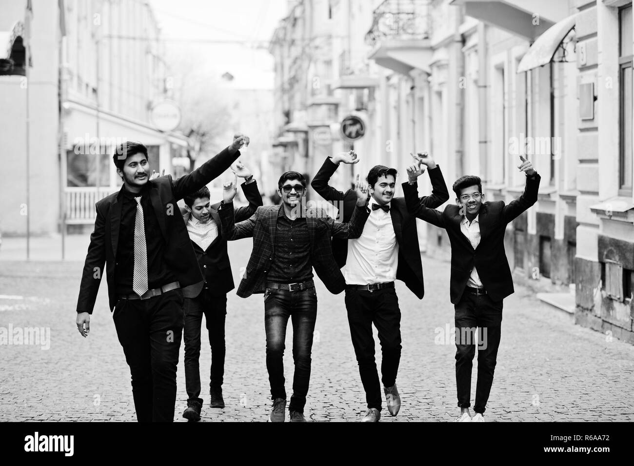 Group of 5 indian students in suits posed outdoor, having fun and dancing. Stock Photo