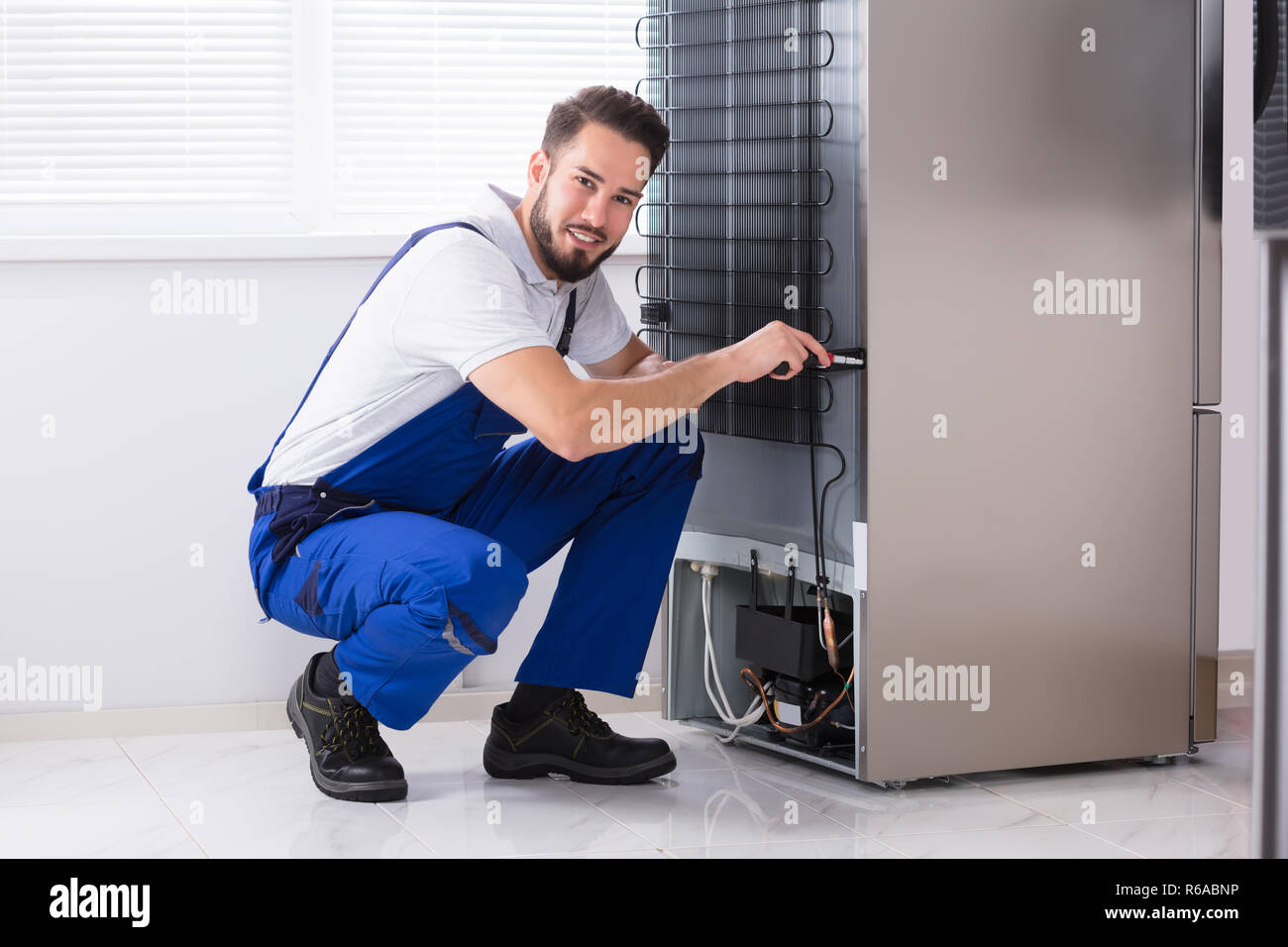 Technician Fixing Refrigerator Stock Photo