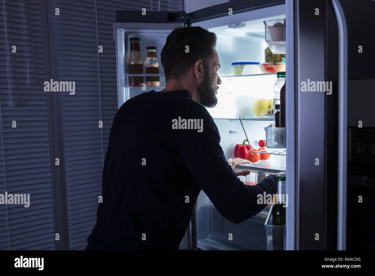 Man Looking At Food Kept In Refrigerator Stock Photo