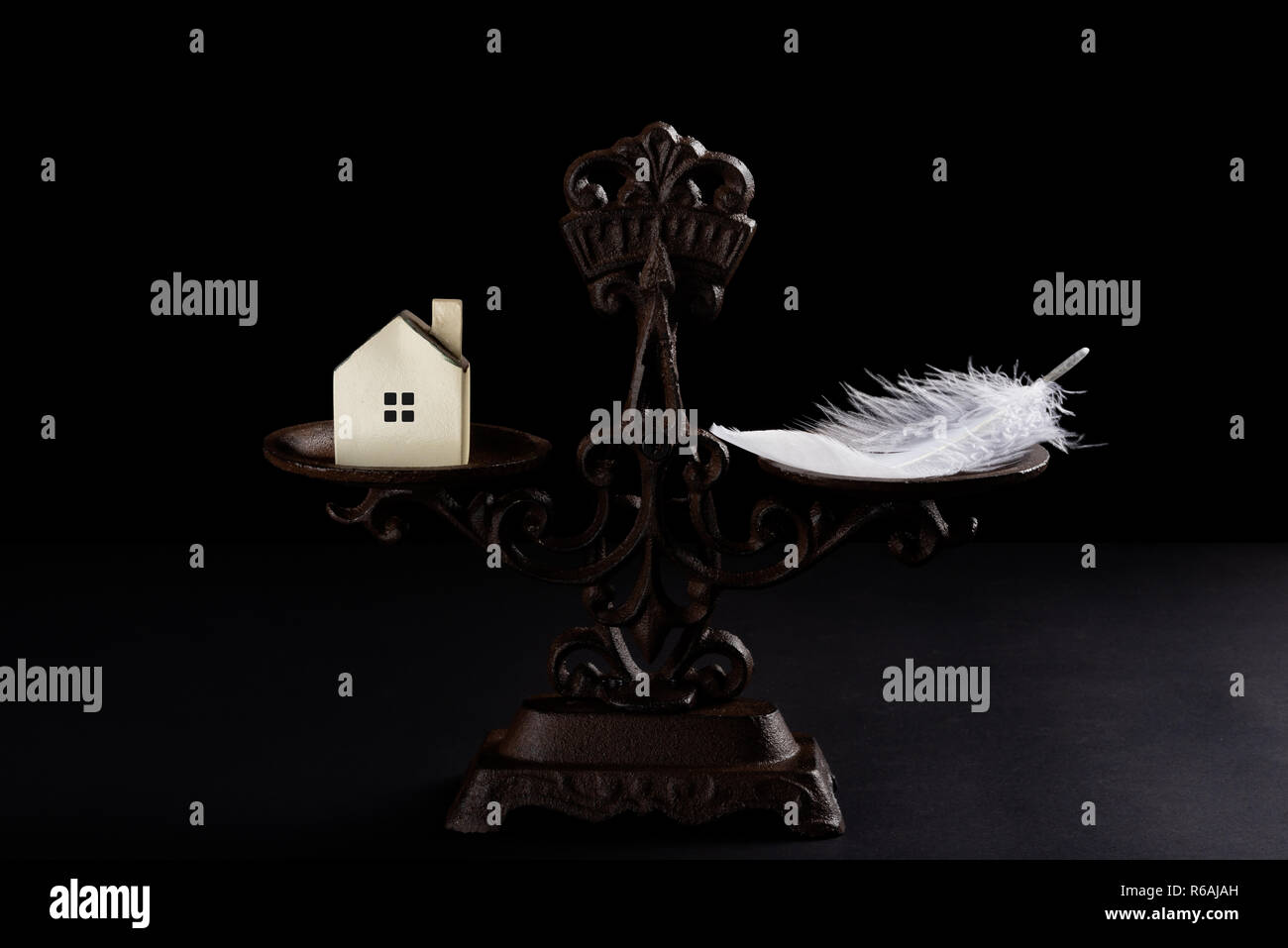 house and feather on a balanced scale concept of the value of houses worthless Stock Photo
