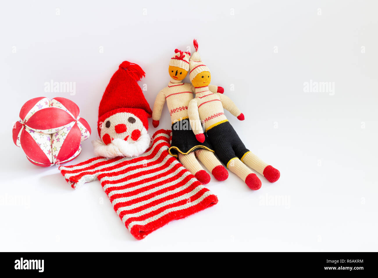 Front view of funny vintage children toys on white background. Assortment consists of a clown, a male doll, a female doll, and a ball. Stock Photo