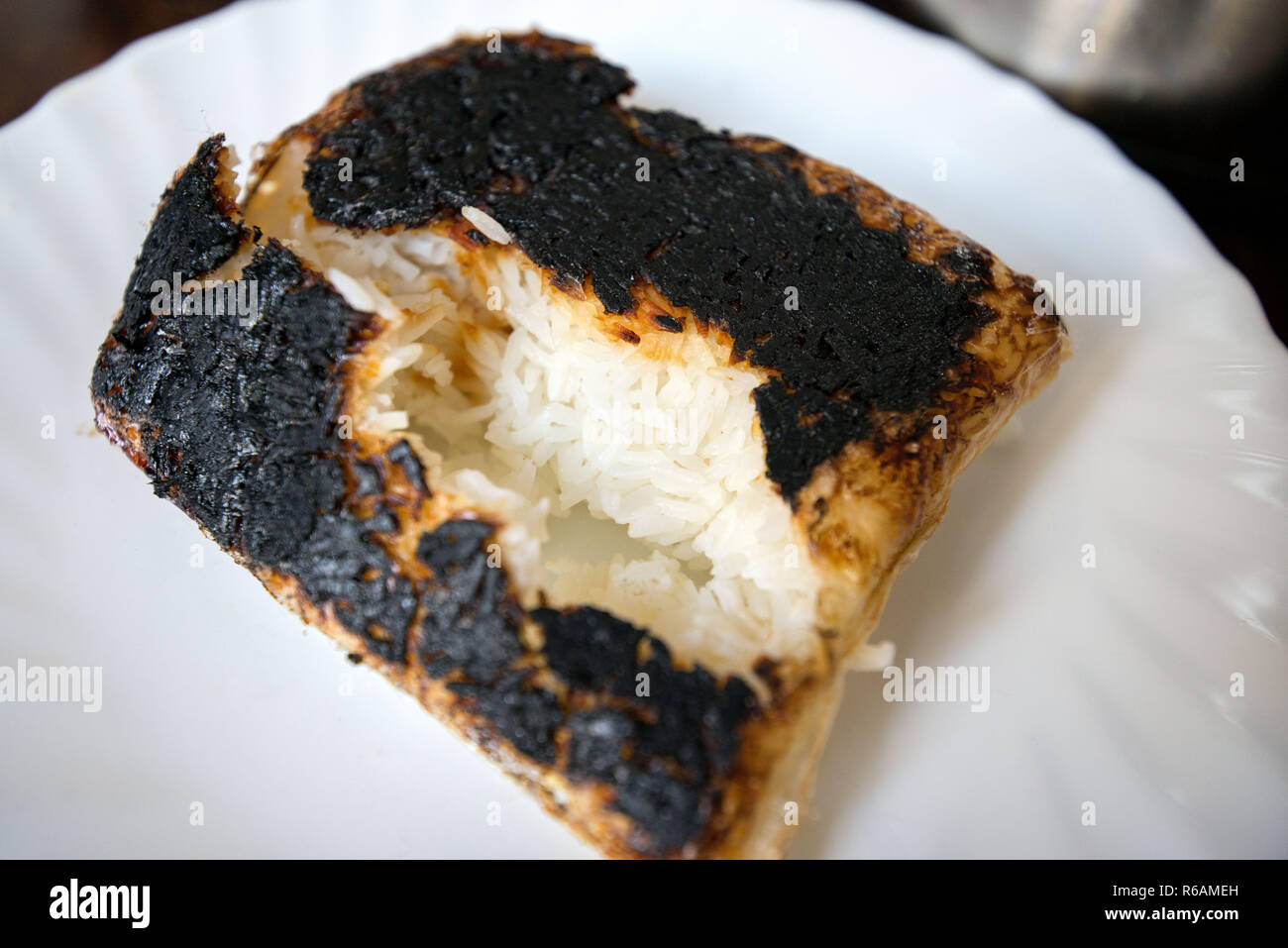 Completely burnt rice on plate next to pot standing on table in kitchen. Concept of unskilled
