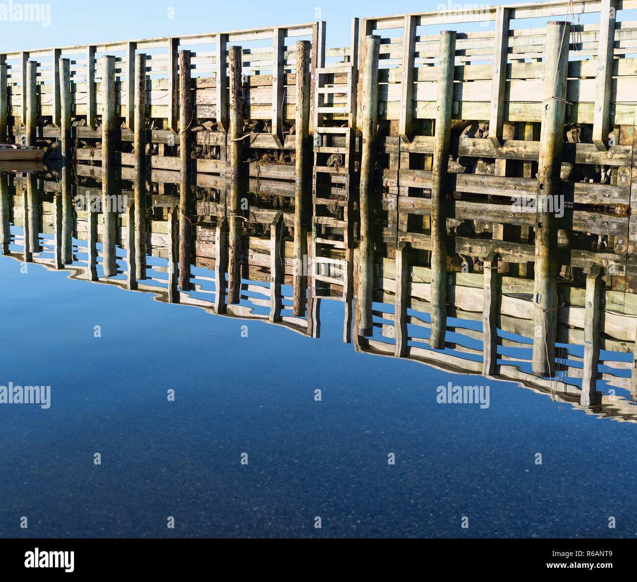 Wide view of the public pier reflected on the water at Penobscot Bay at Searsport, Maine in the